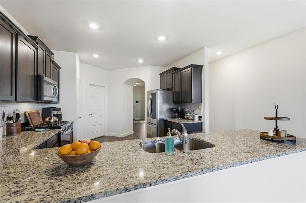 949 Philadelphia Street Fate, TX 75189 - Photo 12 of 36 a kitchen with stainless steel appliances granite countertop a sink and a refrigerator