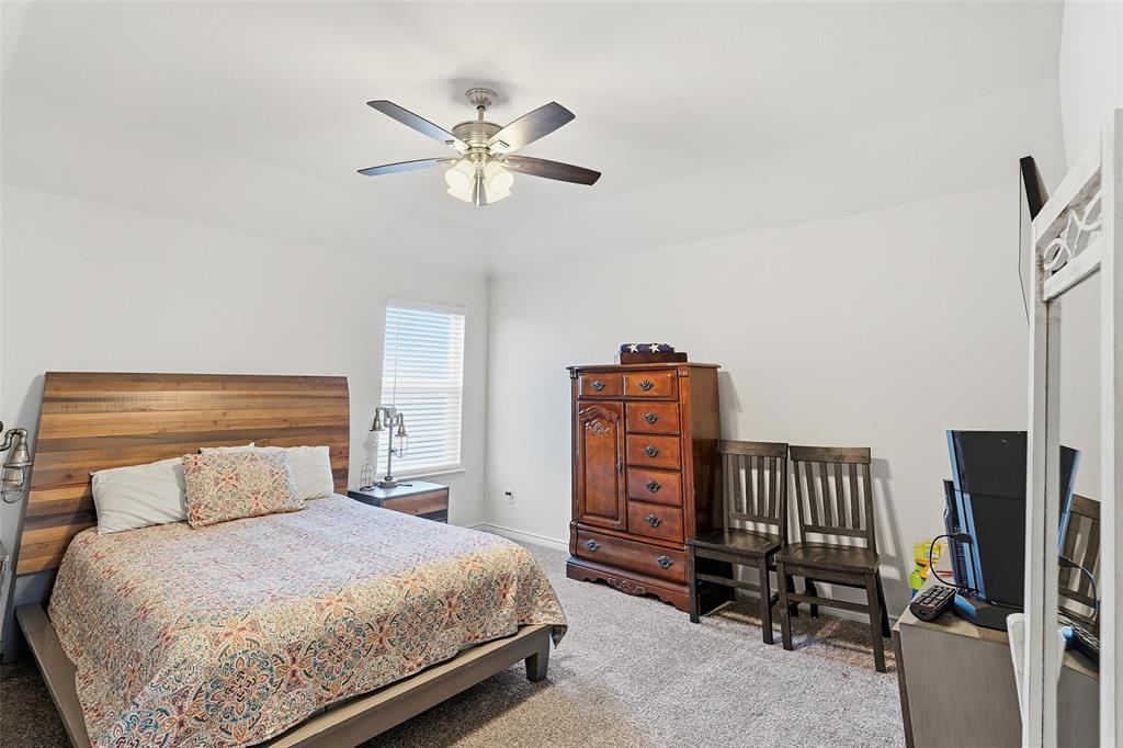 949 Philadelphia Street Fate, TX 75189 - Photo 20 of 36 a bedroom with a bed a chandelier and dresser