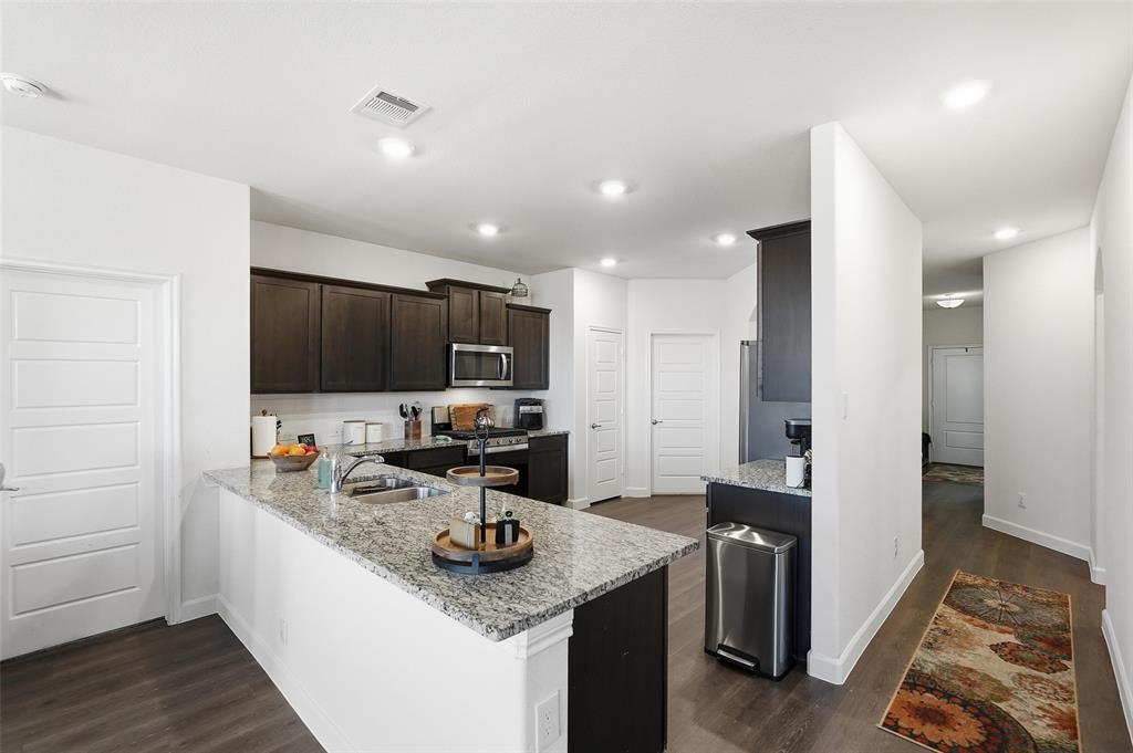 949 Philadelphia Street Fate, TX 75189 - Photo 9 of 36 a kitchen with stainless steel appliances kitchen island granite countertop a sink stove and refrigerator