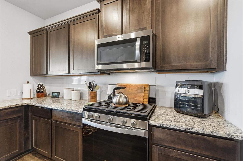 949 Philadelphia Street Fate, TX 75189 - Photo 10 of 36 a kitchen with granite countertop cabinets stainless steel appliances and wooden floor