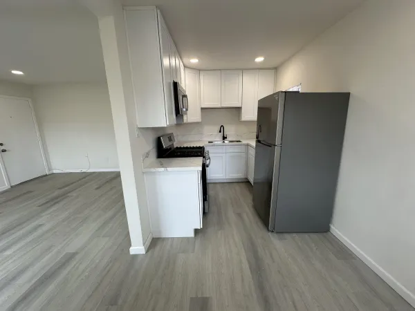 a kitchen with a refrigerator a stove top oven a sink and wooden floor