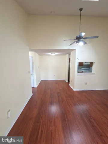 a view of empty room with wooden floor and ceiling fan