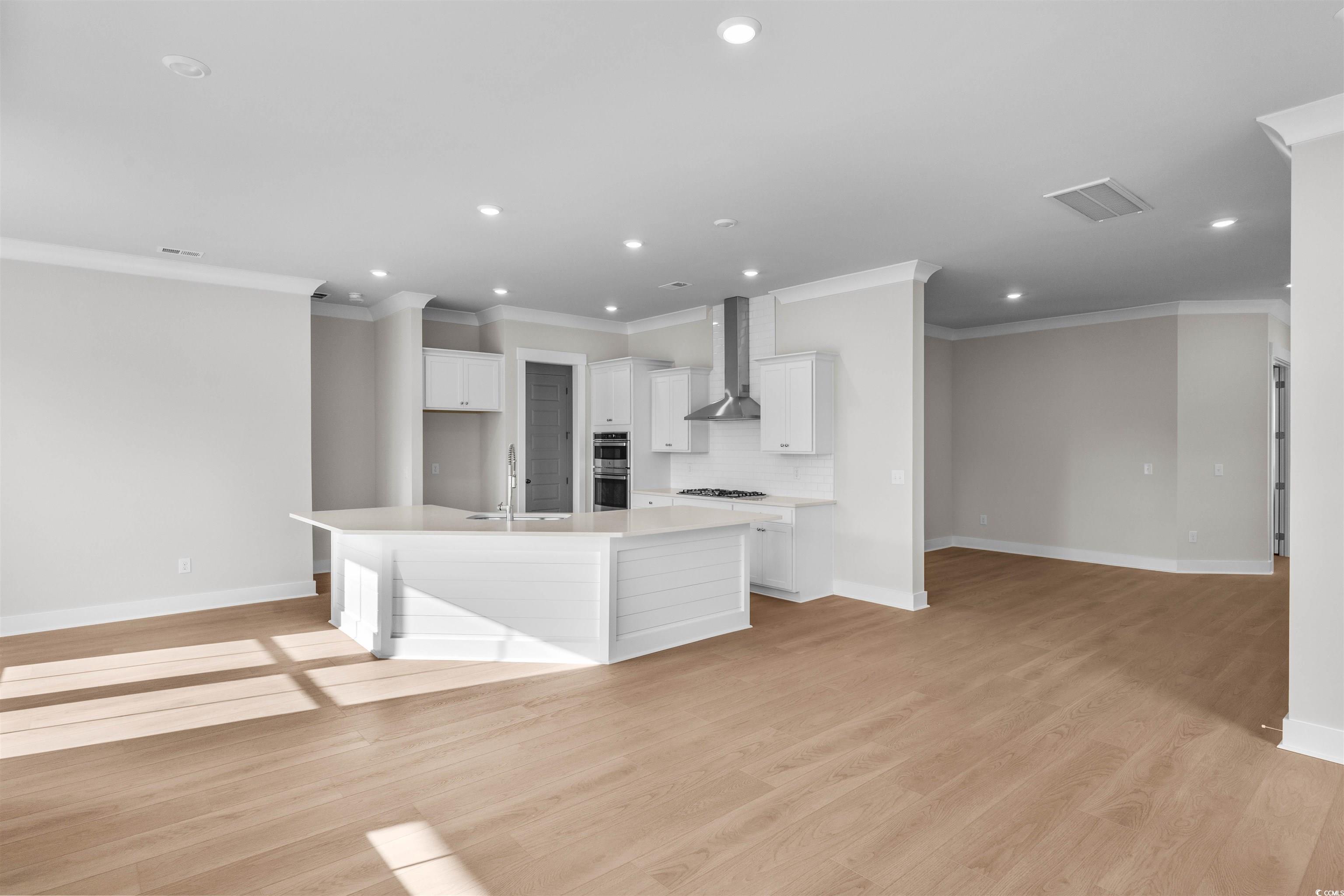 229 Atlantic Breeze Street Myrtle Beach, SC 29572 - Photo 13 of 24 Kitchen featuring white cabinetry, crown molding, tasteful backsplash, a kitchen island with sink, and recessed lighting