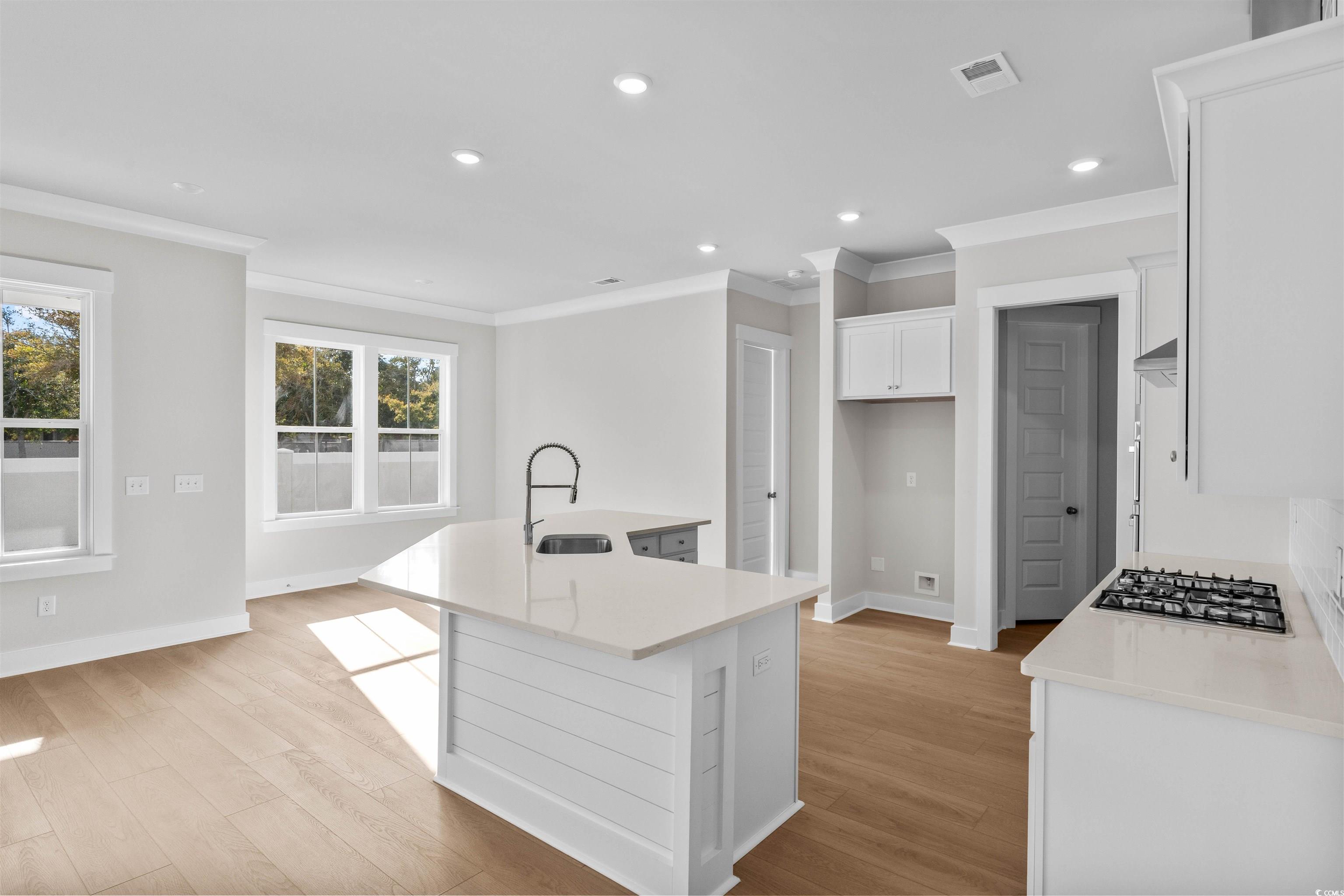 229 Atlantic Breeze Street Myrtle Beach, SC 29572 - Photo 14 of 24 Kitchen featuring a kitchen island with sink, light stone counters, recessed lighting, white cabinets, and crown molding