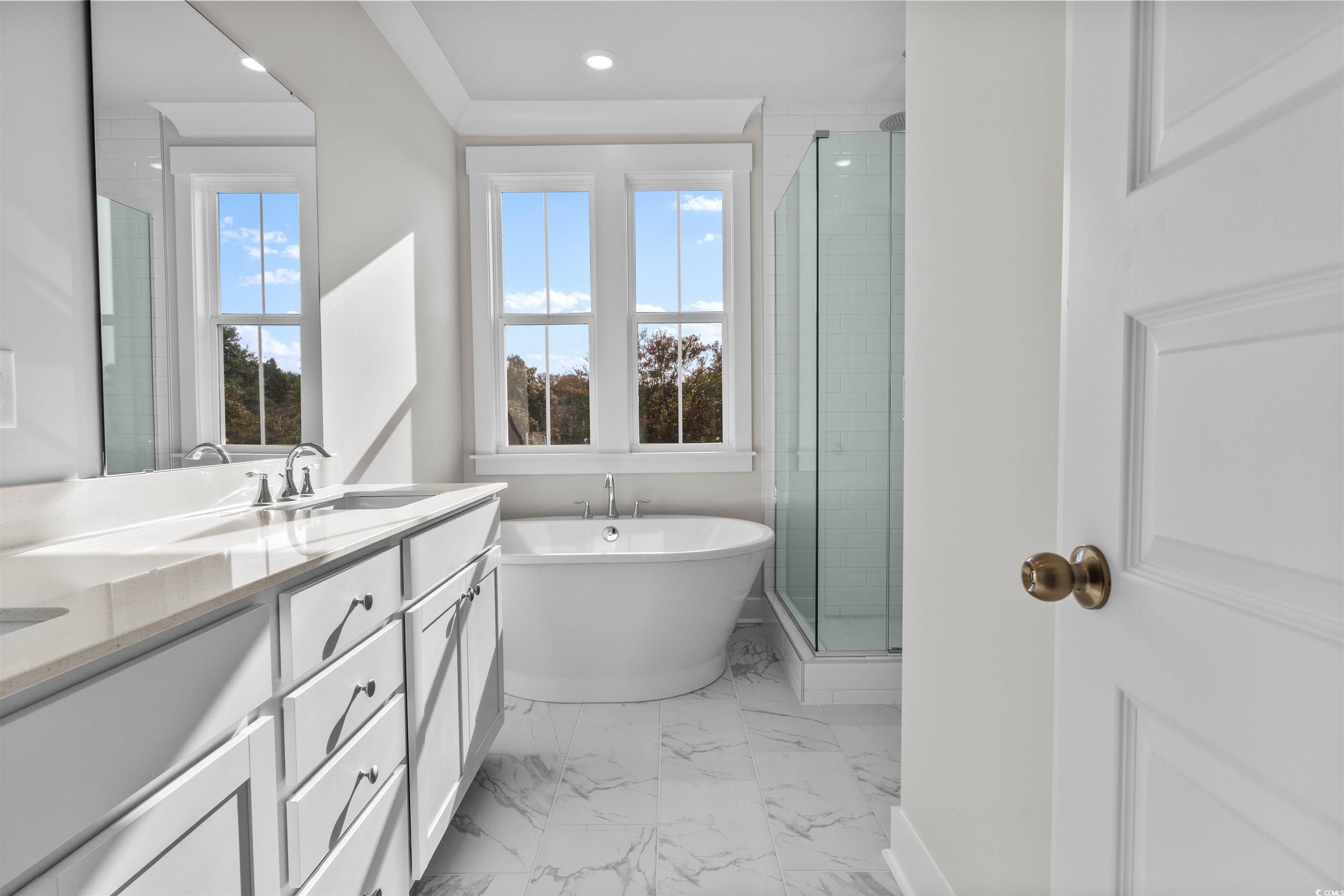 229 Atlantic Breeze Street Myrtle Beach, SC 29572 - Photo 18 of 24 Full bath featuring double vanity, a freestanding bath, a shower stall, light marble finish floors, and plenty of natural light