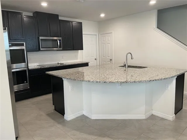 a kitchen with stainless steel appliances granite countertop a sink and a microwave