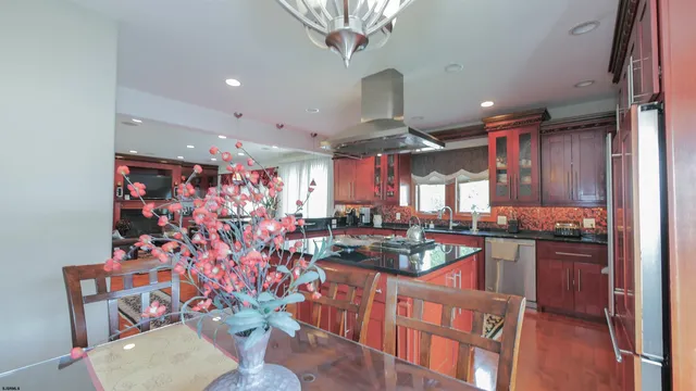 a kitchen with stainless steel appliances granite countertop a stove a sink dishwasher a dining table and chairs with wooden floor