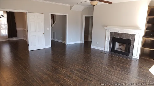 an empty room with wooden floor fireplace and windows