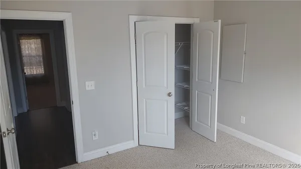 a view of an empty room with closet and wooden door