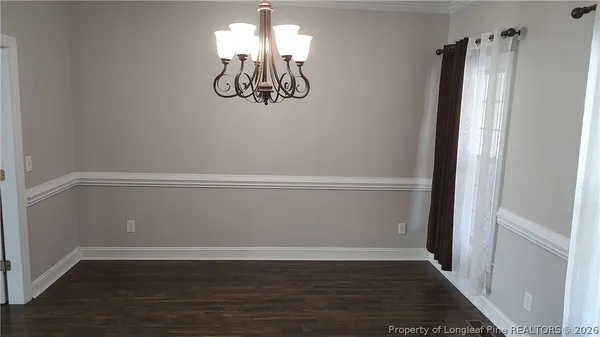 an empty room with wooden floor and chandelier