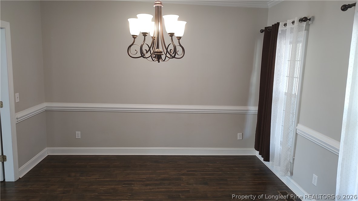 504 Brunswick Road Fayetteville, NC 28303 - Photo 7 of 50 an empty room with wooden floor and chandelier