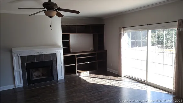 a living room with wooden floor a fireplace and windows