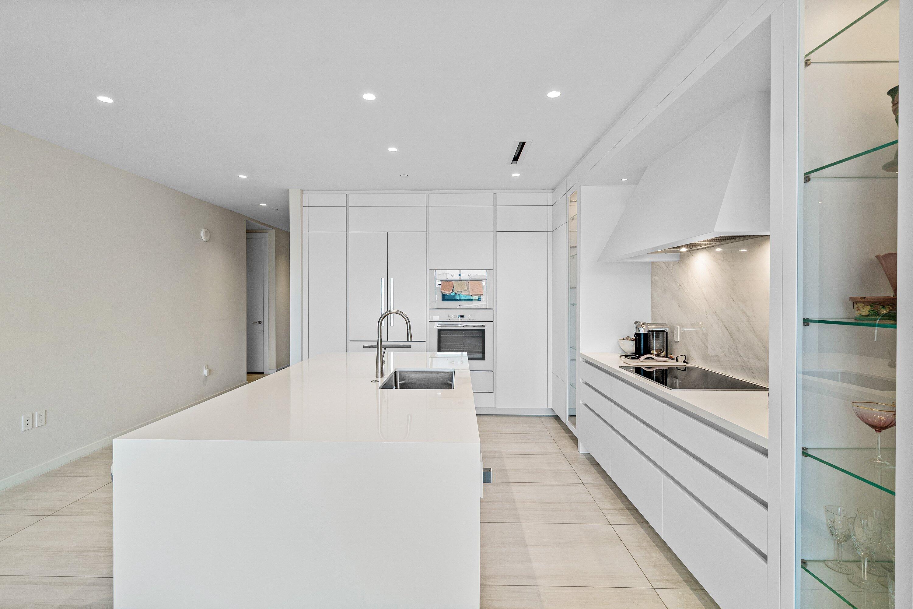 200 Southeast Mizner Boulevard, Unit 810 Boca Raton, FL 33432 - Photo 12 of 29 a large white kitchen with stainless steel appliances a large counter top a stove and a refrigerator