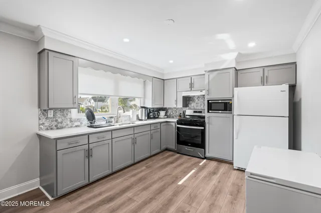 a kitchen with a sink a refrigerator and white cabinets