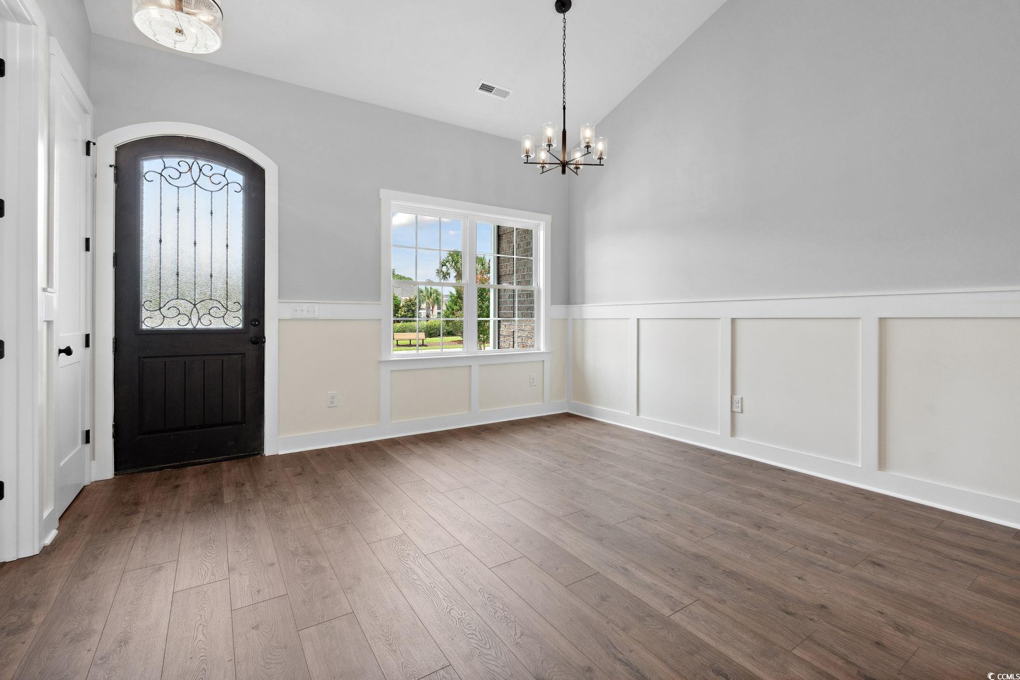 309 Waterfall Circle Little River, SC 29566 - Photo 3 of 40 Entrance foyer with a chandelier, wainscoting, dark wood-type flooring, healthy amount of natural light, and a decorative wall