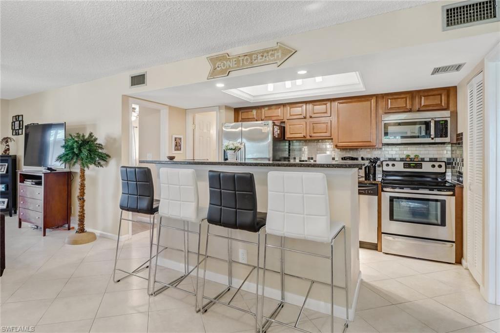 a kitchen with stainless steel appliances granite countertop a stove top oven a sink a dining table and chairs
