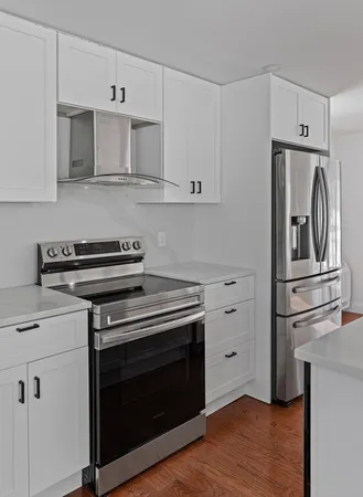 a kitchen with cabinets stainless steel appliances and wooden floor