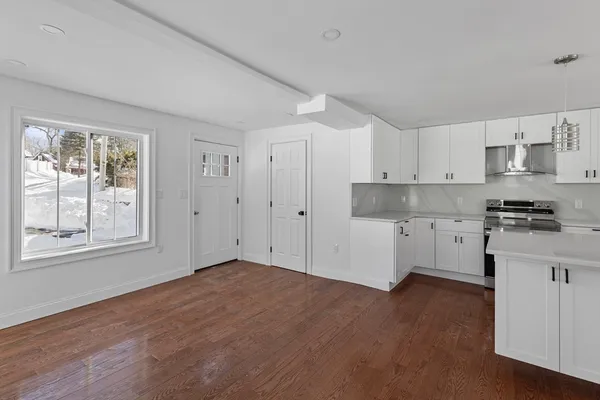 a kitchen with granite countertop white cabinets and wooden floor
