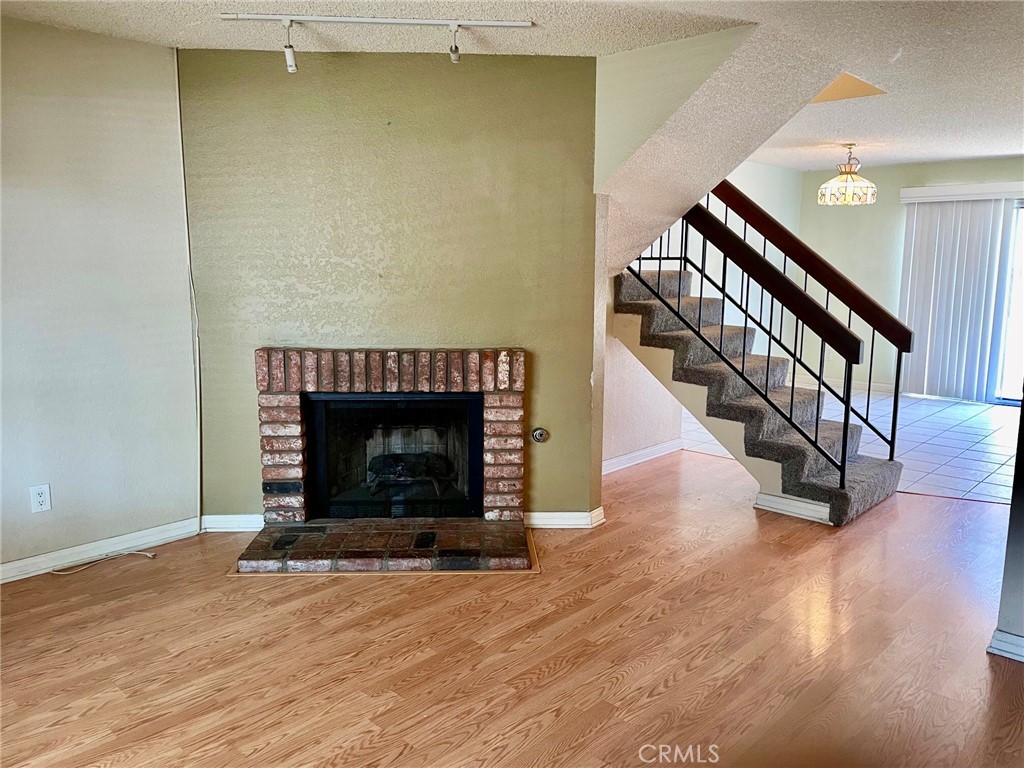 1077 South Santo Antonio Drive, Unit 15 Colton, CA 92324 - Photo 3 of 20 a view of an empty room with wooden floor fireplace and a window