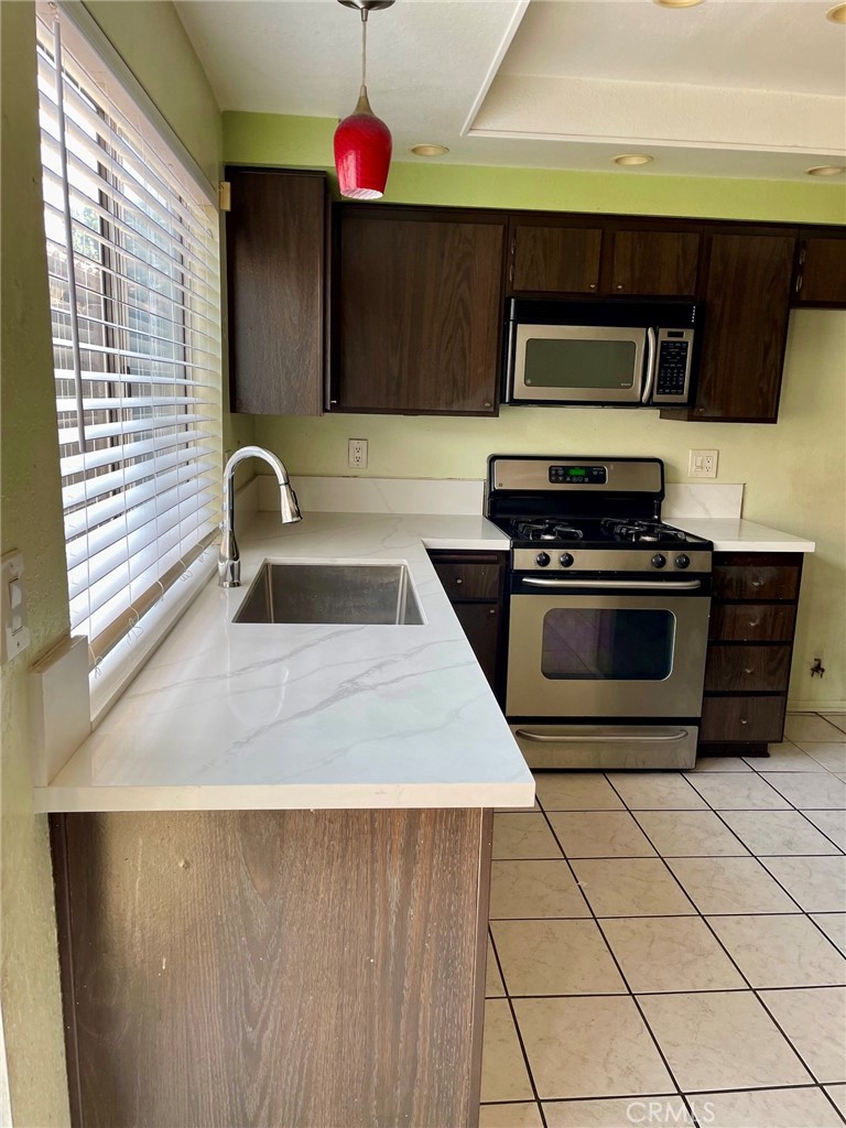 1077 South Santo Antonio Drive, Unit 15 Colton, CA 92324 - Photo 7 of 20 a kitchen with a sink a stove and cabinets