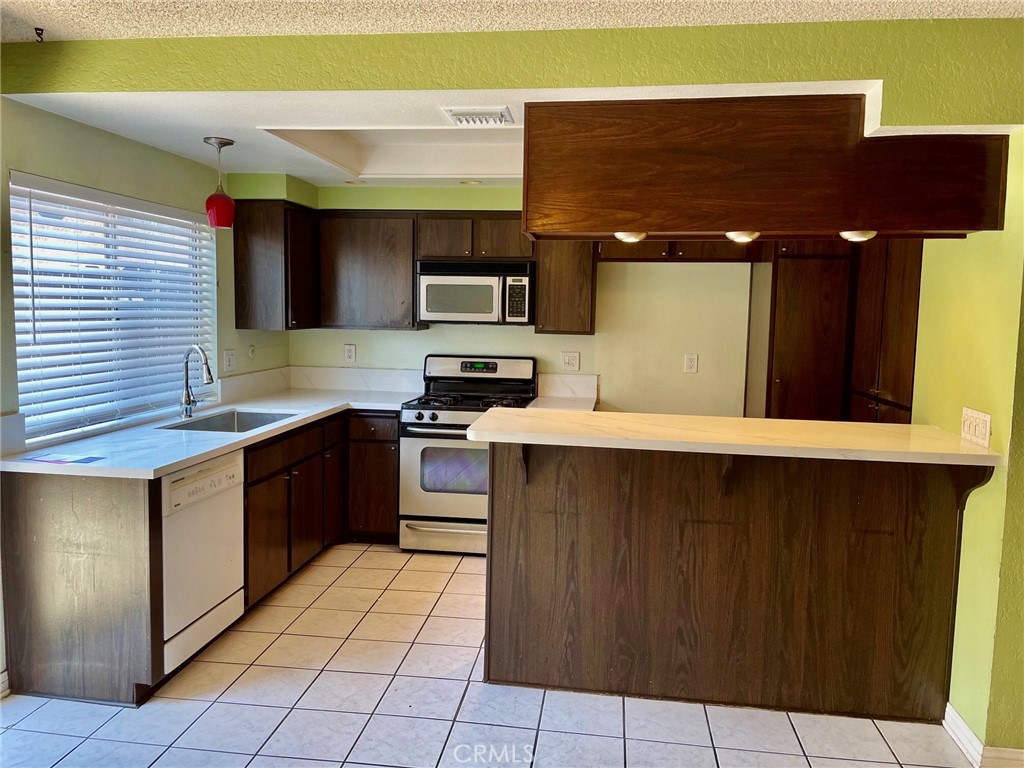 1077 South Santo Antonio Drive, Unit 15 Colton, CA 92324 - Photo 8 of 20 a kitchen with stainless steel appliances a sink and a microwave
