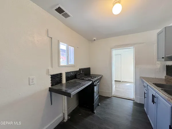 a kitchen with granite countertop a sink stove and cabinets