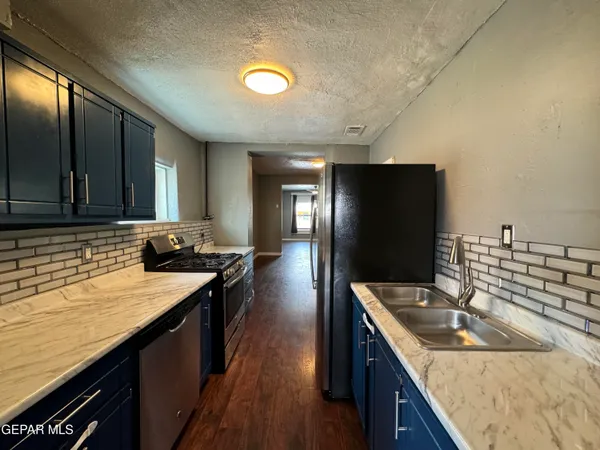 a kitchen with granite countertop a sink a stove and cabinets
