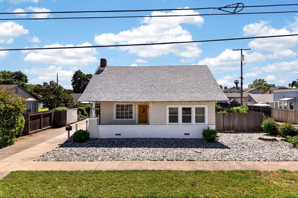 a front view of a house with a yard and potted plants