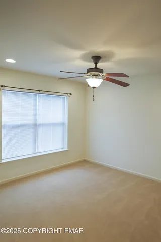 an empty room with a ceiling fan and window
