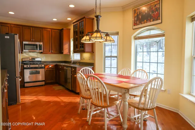 a kitchen with stainless steel appliances granite countertop a stove top oven a sink a dining table and chairs