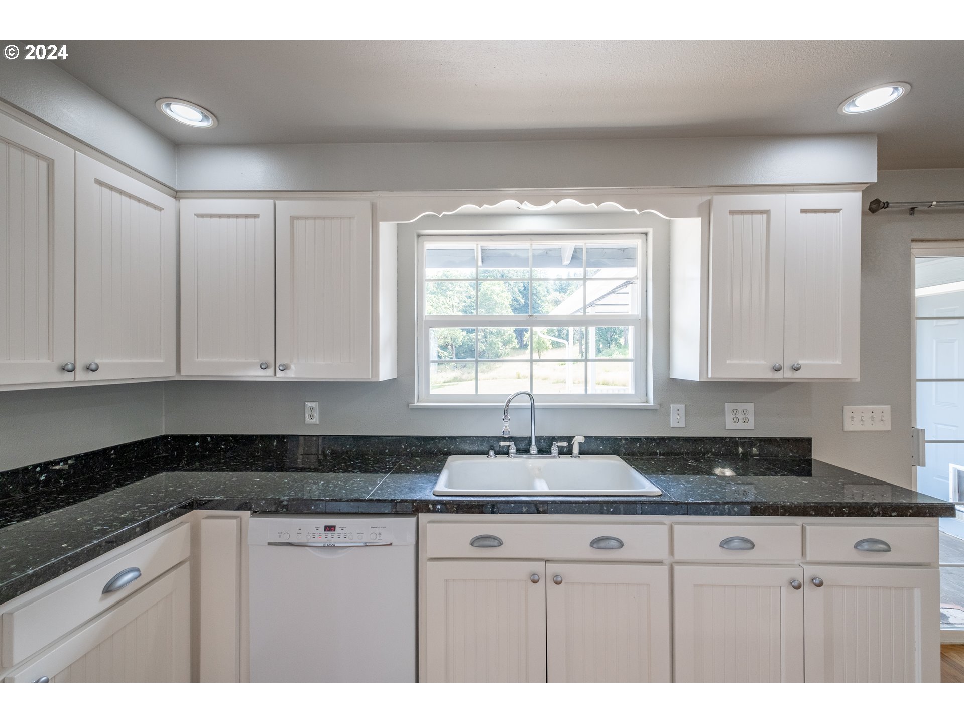 30521 Rancho Road Lebanon, OR 97355 - Photo 12 of 39 a kitchen with granite countertop white cabinets sink and window