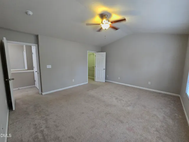 an empty room with a chandelier fan and windows