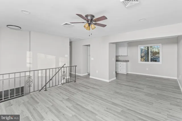 a view of empty room with wooden floor and ceiling fan
