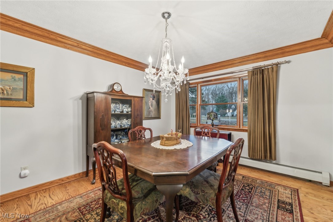 6326 Murray Ridge Road Elyria, OH 44035 - Photo 12 of 49 Dining space with a chandelier, ornamental molding, light hardwood / wood-style floors, and a baseboard heating unit