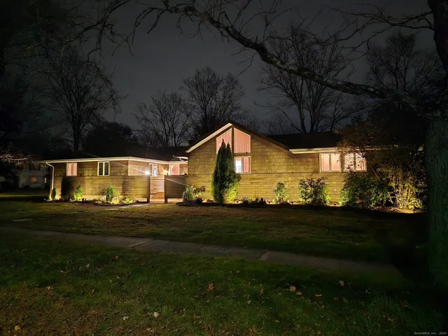 a view of a house with a yard and large trees