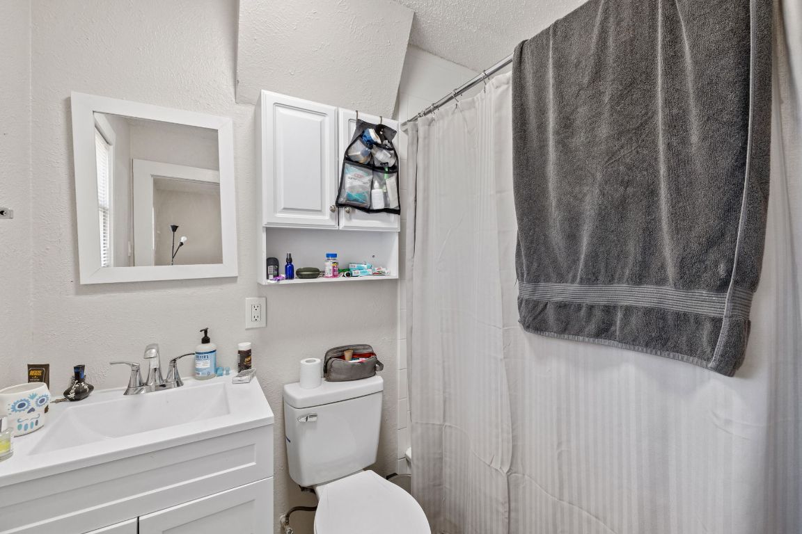 1202 East 29th Street, Unit A Austin, TX 78722 - Photo 19 of 37 Bathroom with vanity, curtained shower, and a textured wall