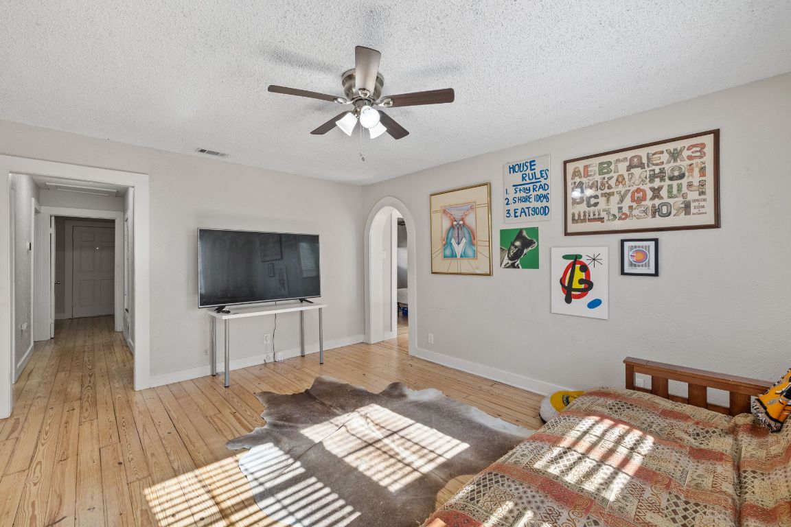 1202 East 29th Street, Unit A Austin, TX 78722 - Photo 8 of 37 Bedroom with a textured ceiling, arched walkways, light wood-style flooring, and ceiling fan