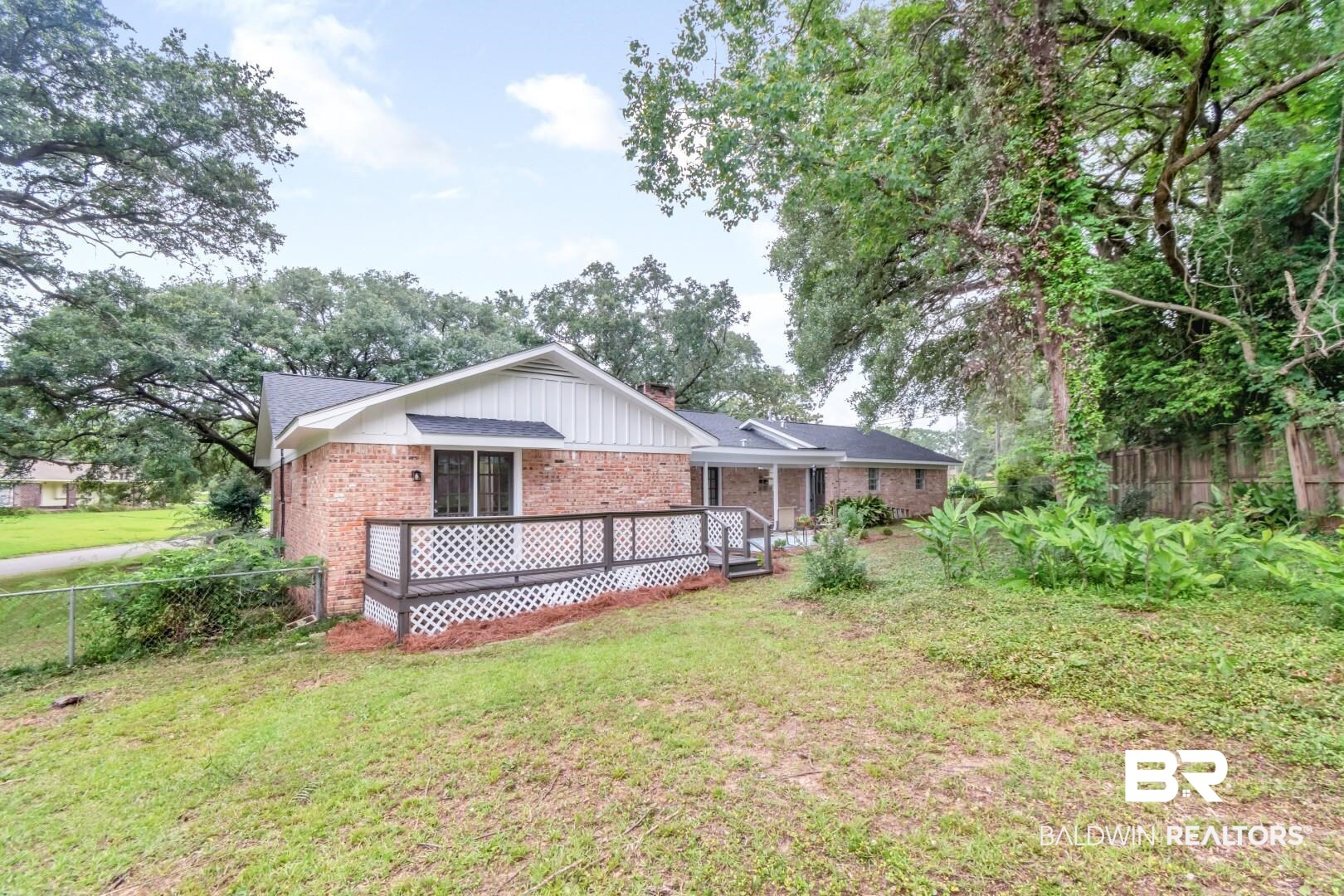 5217 Perin Road Mobile, AL 36693 - Photo 39 of 45 Brick residence featuring a gabled roofline, white fascia, and a wood deck with lattice skirting