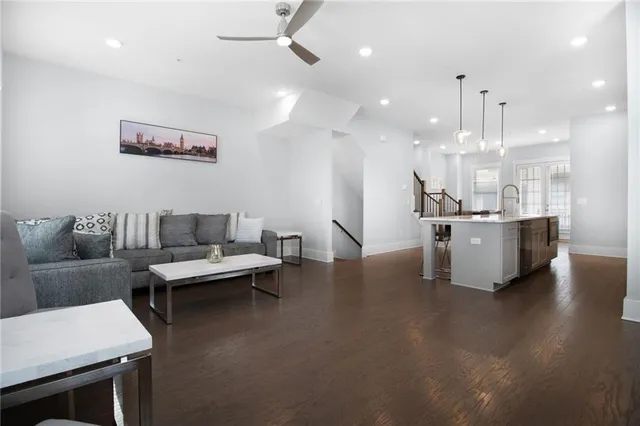 a living room with couches and kitchen view with wooden floor