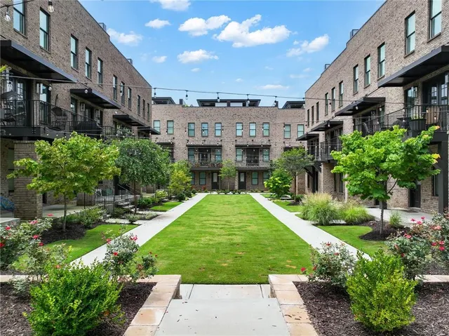 a view of a big building with a yard and plants