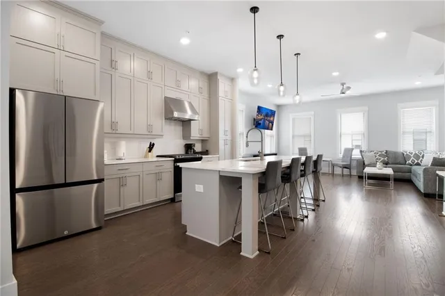 a kitchen with stainless steel appliances a refrigerator a stove a sink dishwasher and a dining table with wooden floor