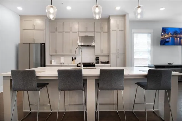 a kitchen with kitchen island granite countertop a dining table chairs refrigerator and cabinets