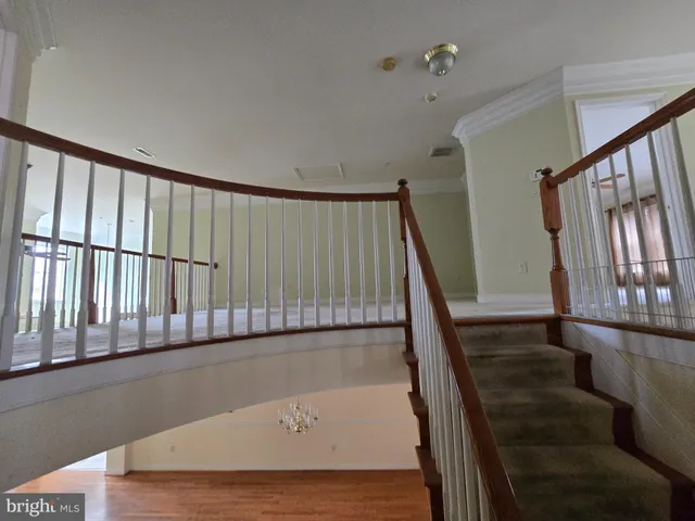 a view of staircase with railing and white walls