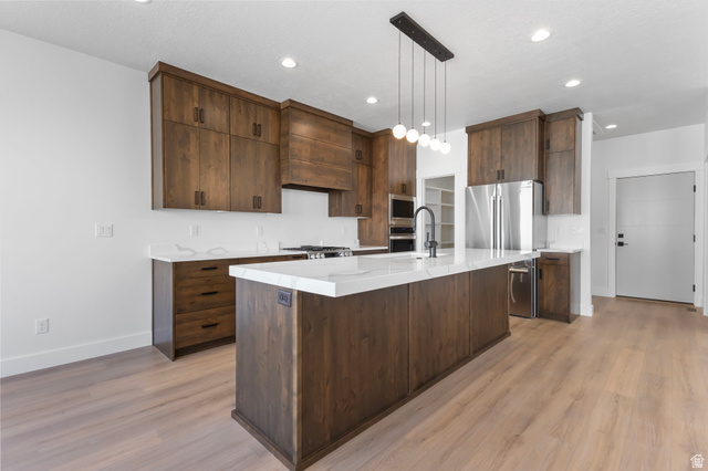 710 East Mountain Road North Ogden, UT 84414 - Photo 9 of 36 Kitchen with stainless steel appliances, pendant lighting, light stone counters, and light wood-type flooring