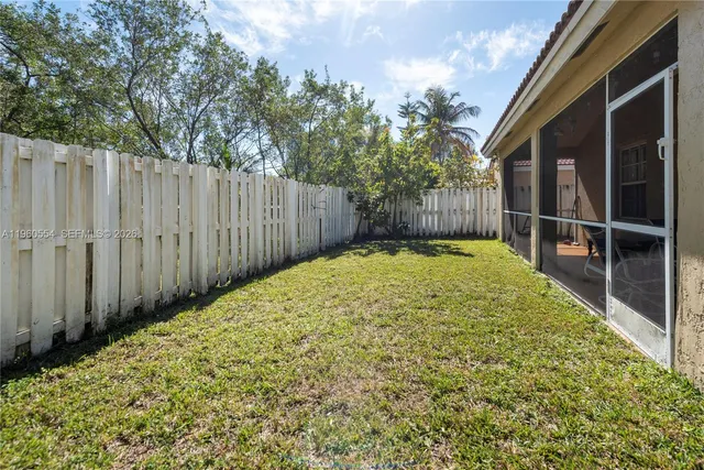 a view of backyard with wooden fence and trees