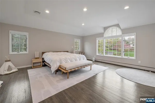 a spacious bedroom with a bed and wooden floor