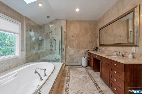 a bathroom with a tub a sink shower and mirror