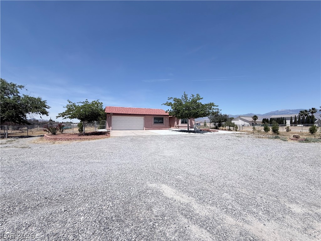 1220 East Gamebird Road Pahrump, NV 89048 - Photo 31 of 49 A terracotta-roofed residence nestled in a spacious gravel lot, offering distant mountain views.