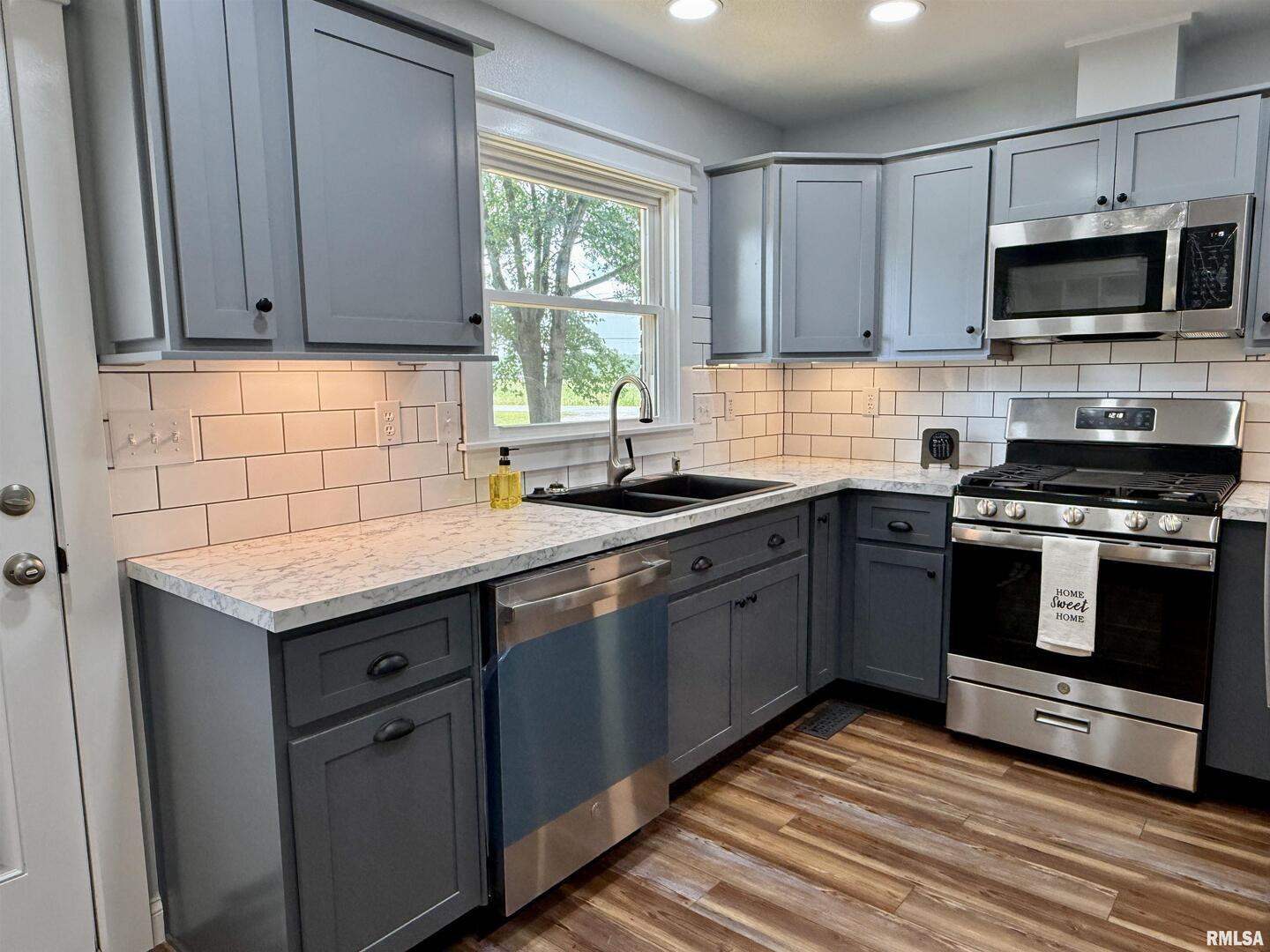 744 Airport Road Metropolis, IL 62960 - Photo 8 of 33 a kitchen with stainless steel appliances granite countertop a sink a stove a microwave and wooden cabinets