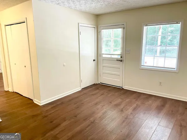 an empty room with wooden floor and windows
